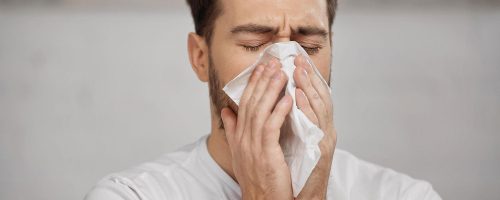 man-with-allergies-sneezing-into-tissue